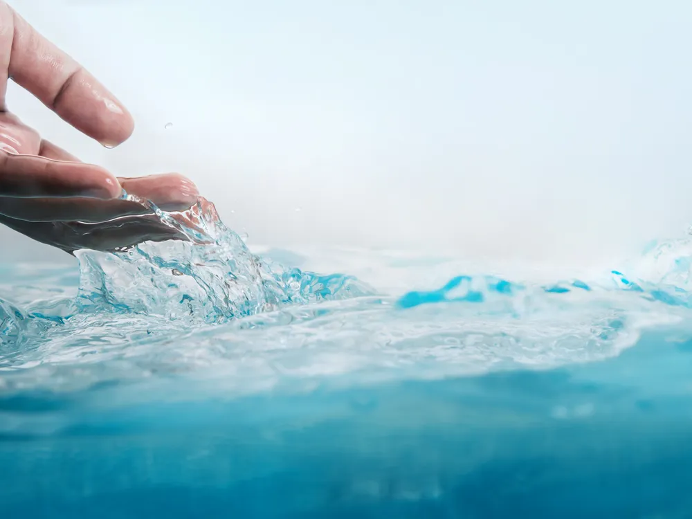 Hand berührt sauberes Wasser – Schutz von Wasser und Sanitärversorgung
